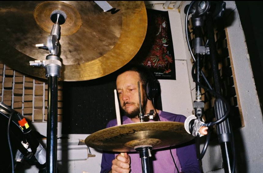 Nebojša Durmanović drumming in a treated studio room, with microphones set up over the kit
